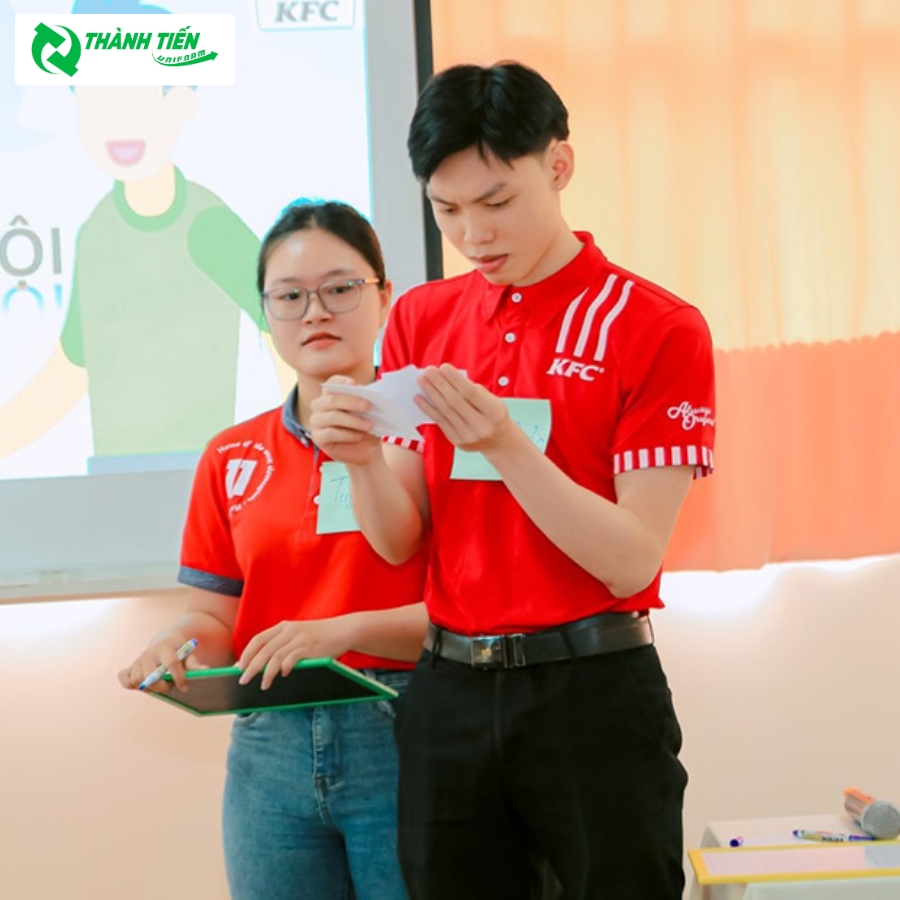 Hình ảnh nhân viên KFC trong trang phục áo thun đồng phục màu đỏ nổi bật.